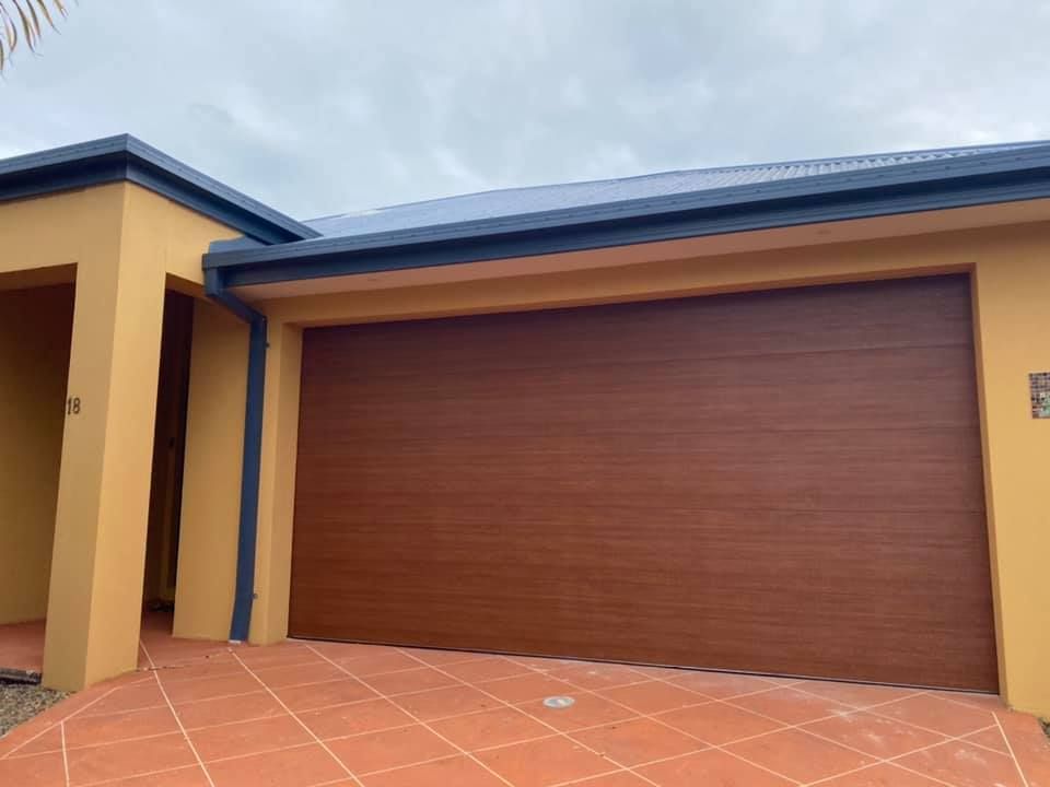 A house with a wooden garage door and a tiled driveway.