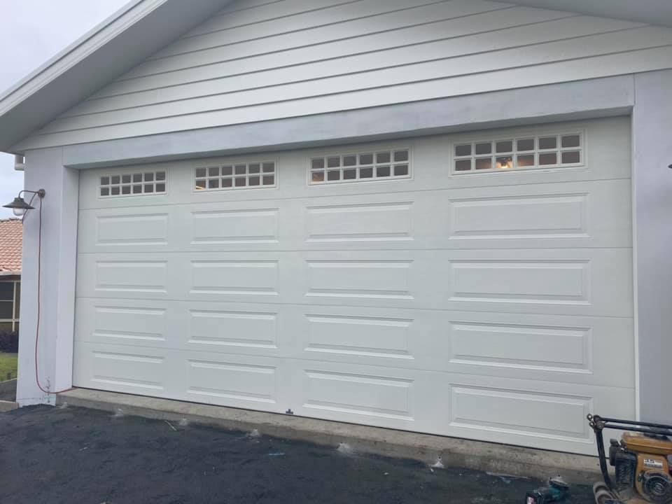 A white garage door is sitting on the side of a house.