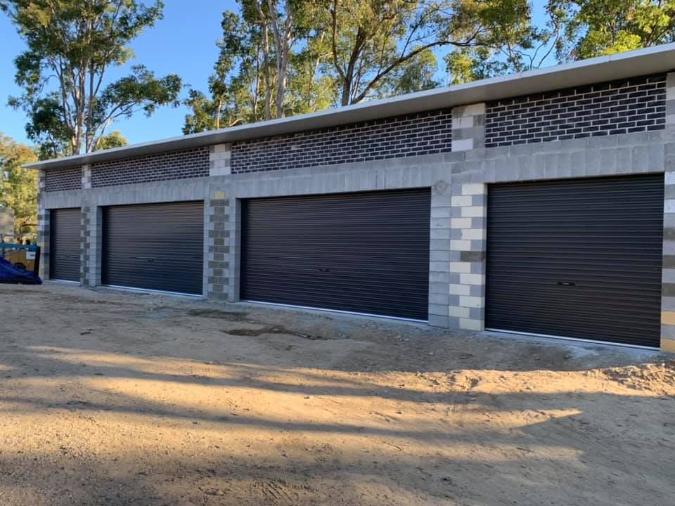 A row of garage doors are lined up next to each other on a dirt road.