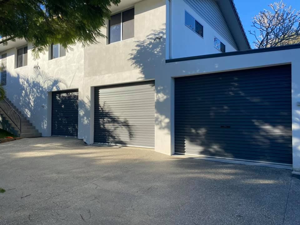 A large white house with two garage doors and a staircase.