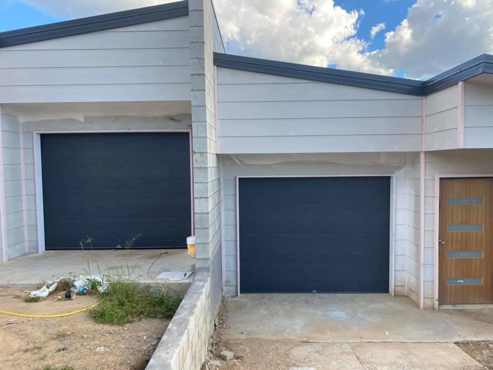 A white house with a black garage door and a wooden door.