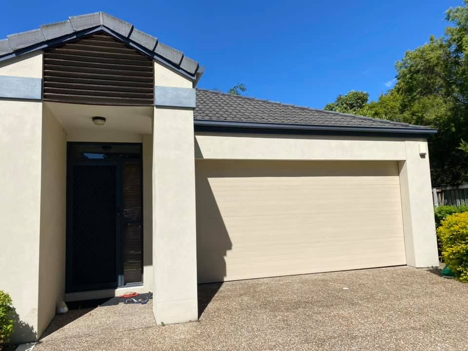 A white house with a garage door and a black door