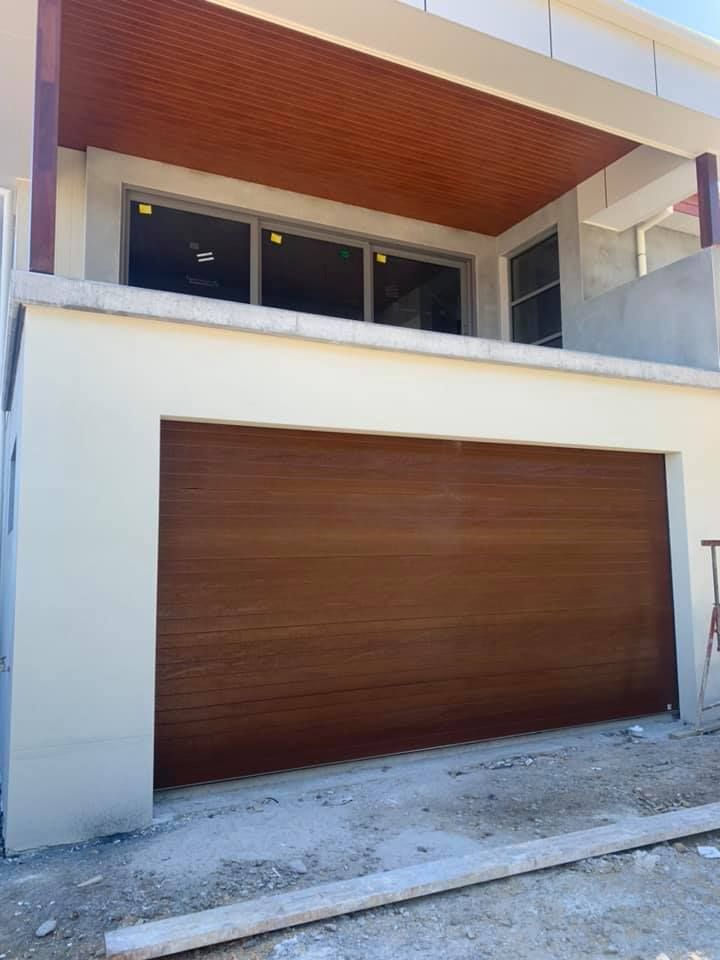 A white house with a wooden garage door and a balcony.