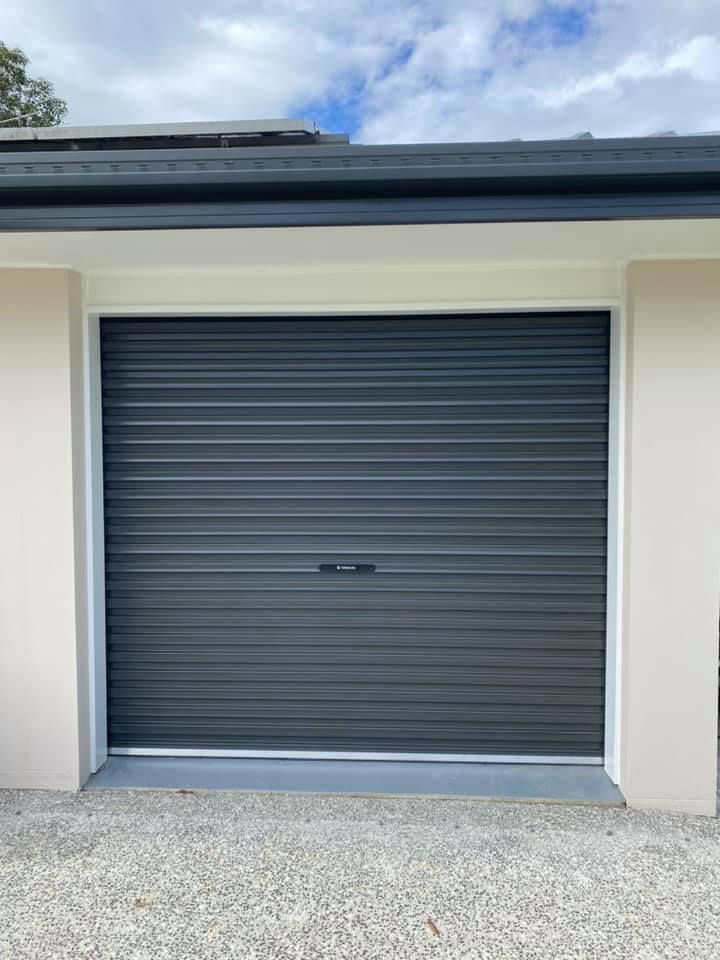 A black garage door is sitting on the side of a house.