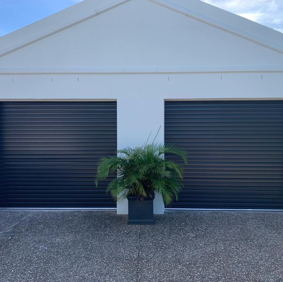 A potted plant is sitting in front of a garage door.