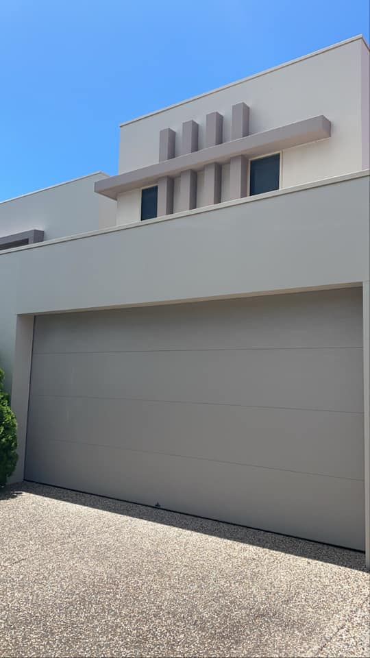 A white house with a large garage door and a blue sky in the background.
