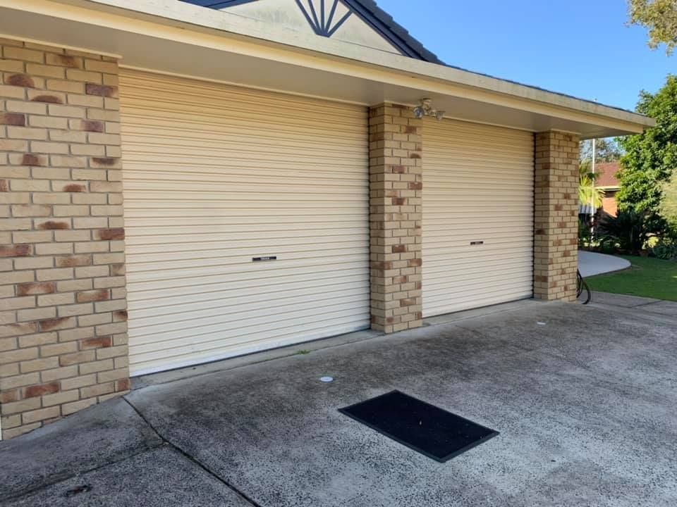 A white garage door is sitting next to a brick building.