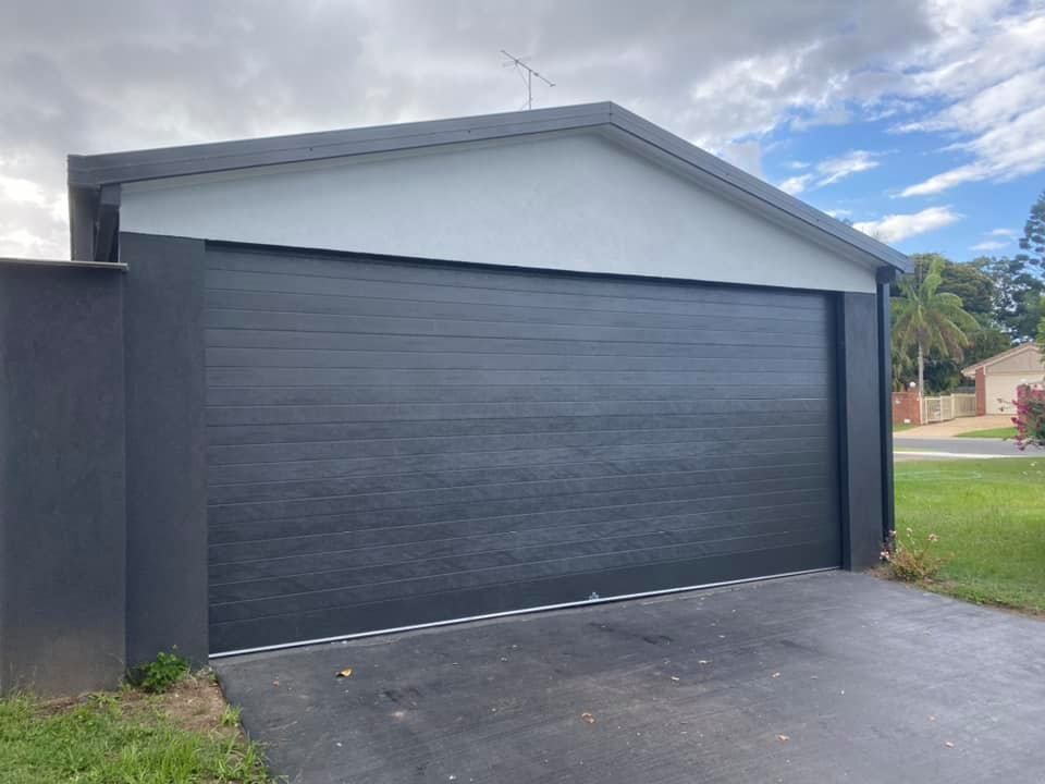 A garage with a black garage door and a white roof.