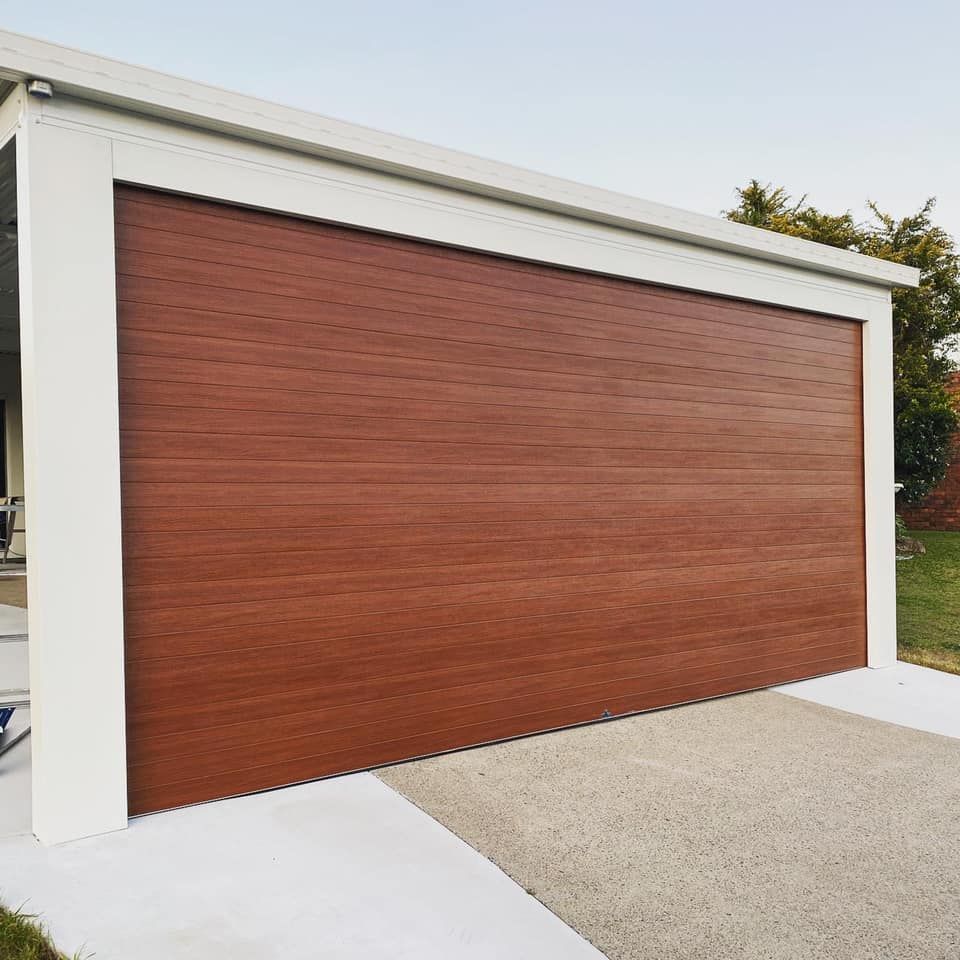 A large wooden garage door is sitting next to a white building.