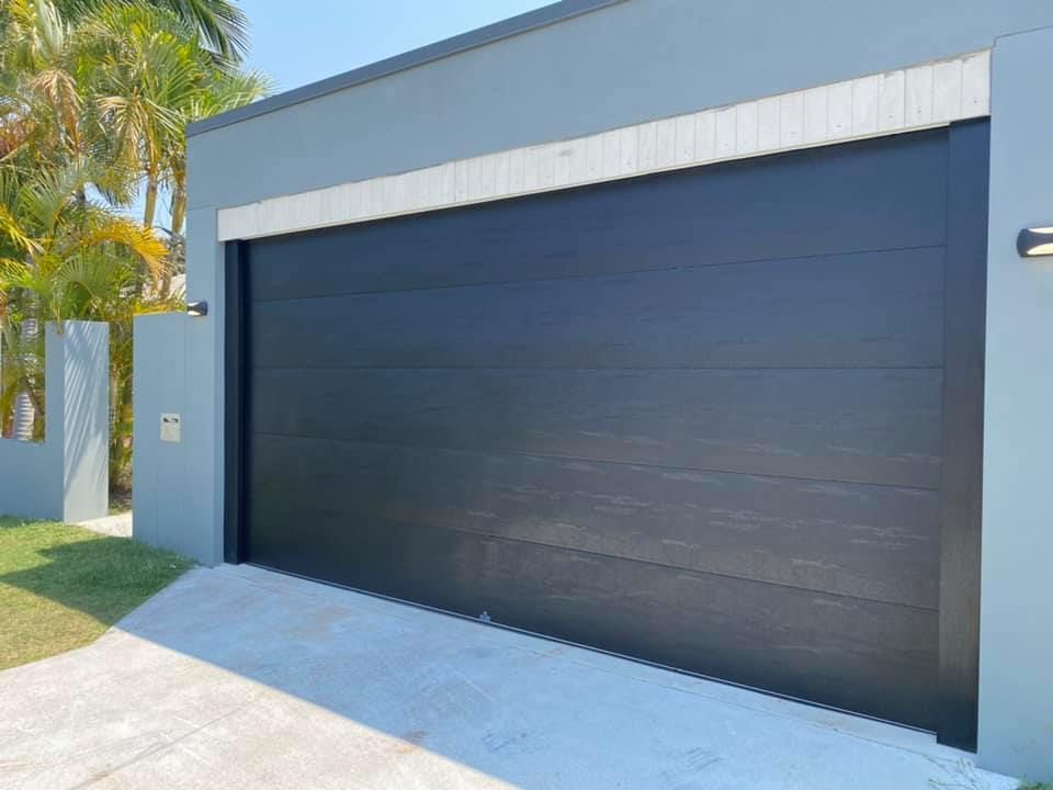 A black garage door is sitting in front of a house.