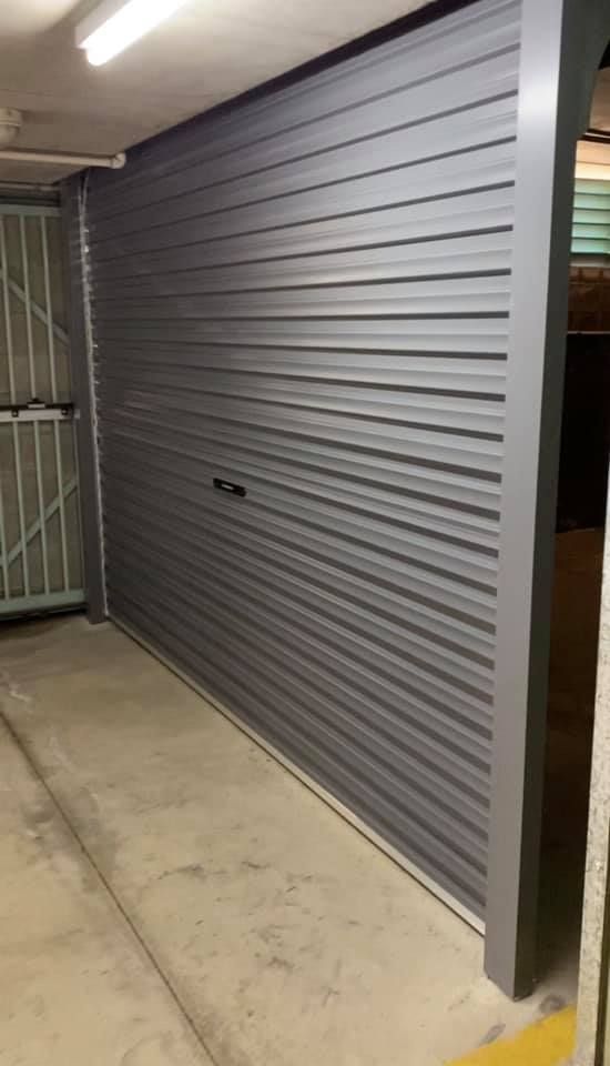A gray garage door is open in a garage.