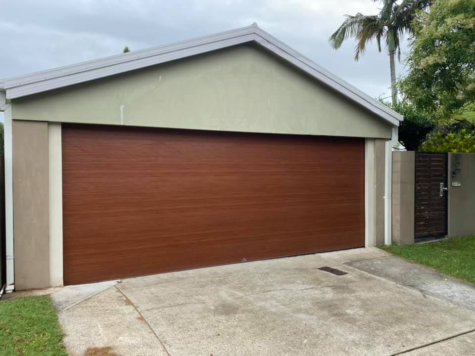 A large brown garage door is sitting in front of a house.