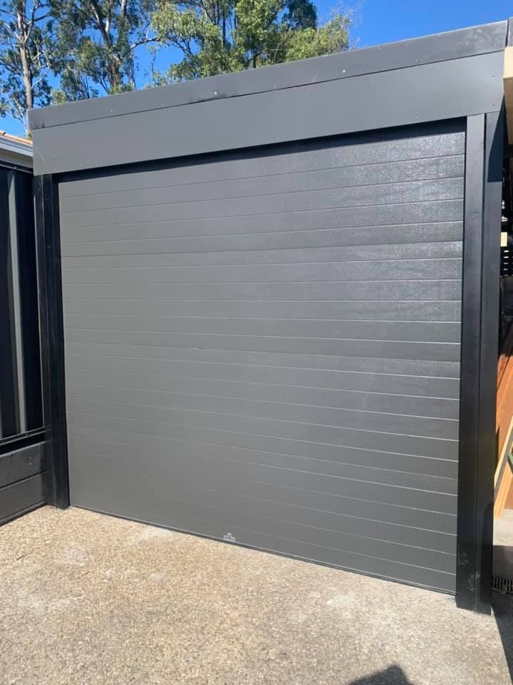 A gray garage door is sitting on top of a concrete driveway.