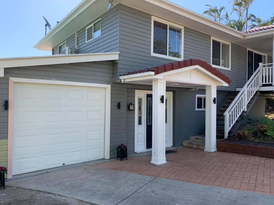 A large gray house with a white garage door and stairs.
