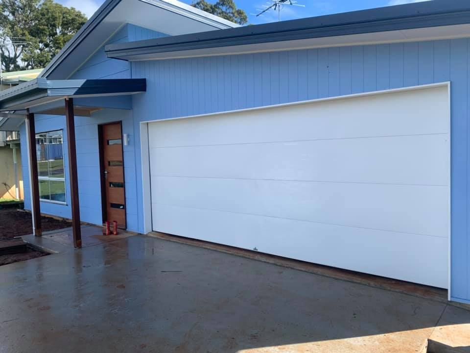 A blue house with a white garage door and a driveway.