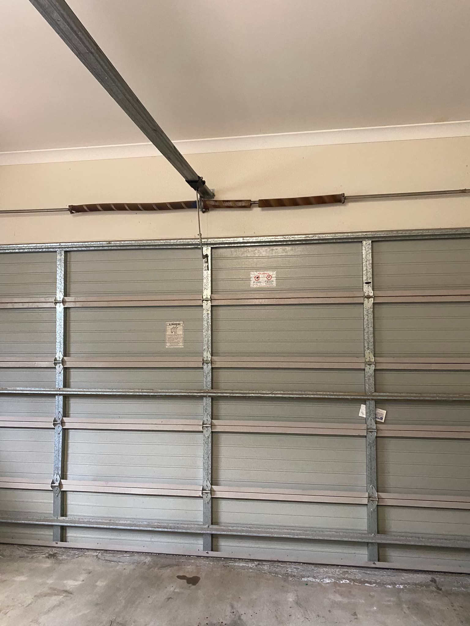 An empty garage with a garage door open and a ceiling fan.
