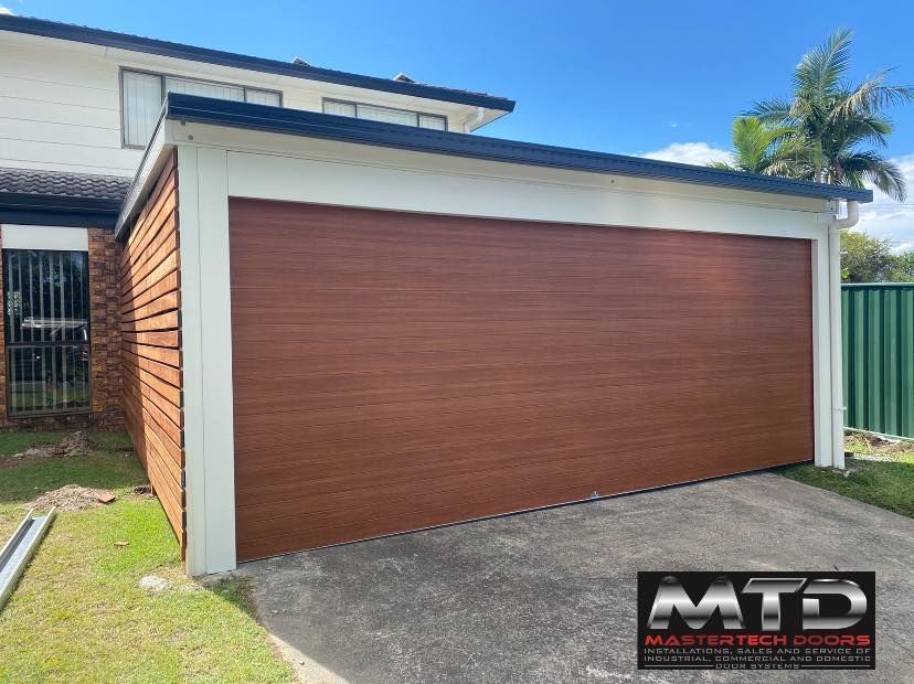 A brown garage door is sitting in front of a house.