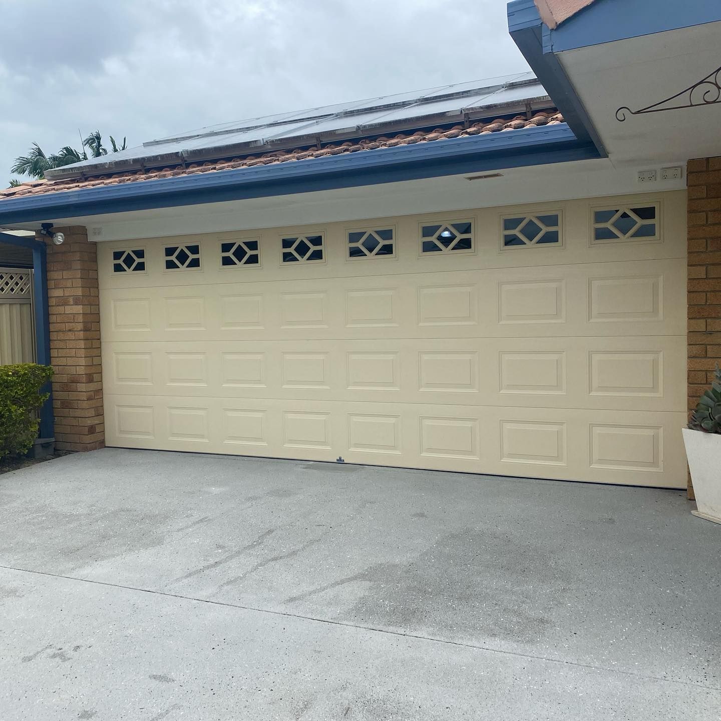 A white garage door is sitting in front of a brick house