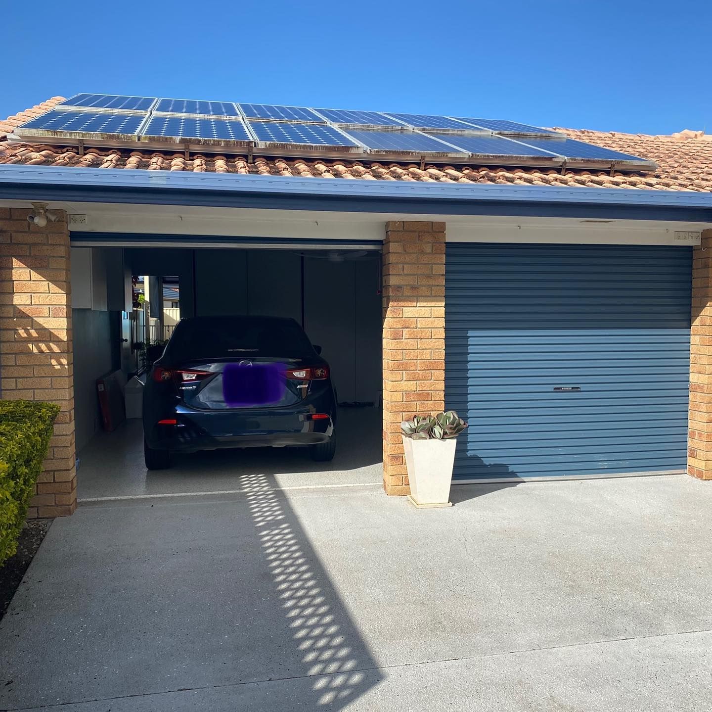 A car is parked in a garage with solar panels on the roof