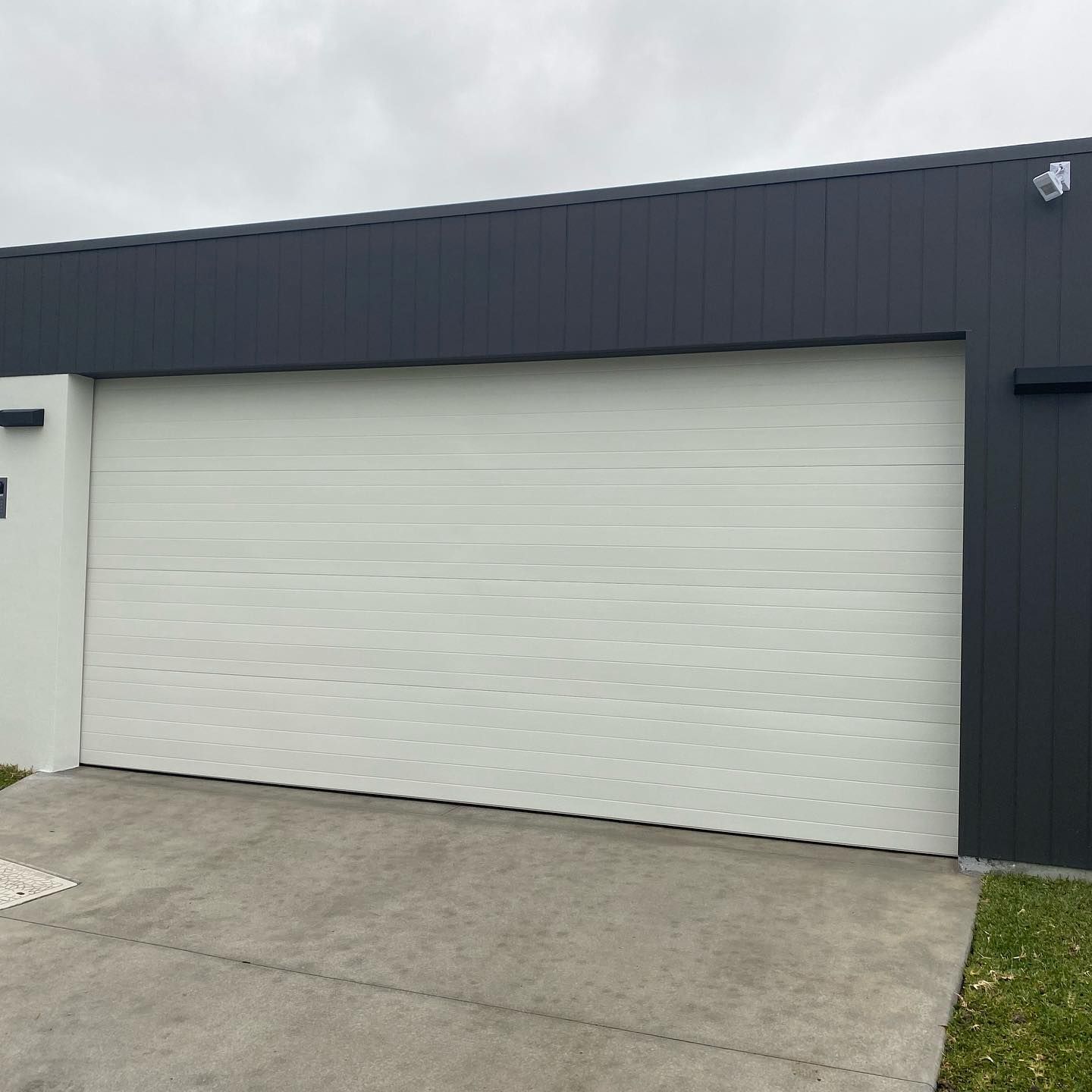 A white garage door is sitting in front of a black building.