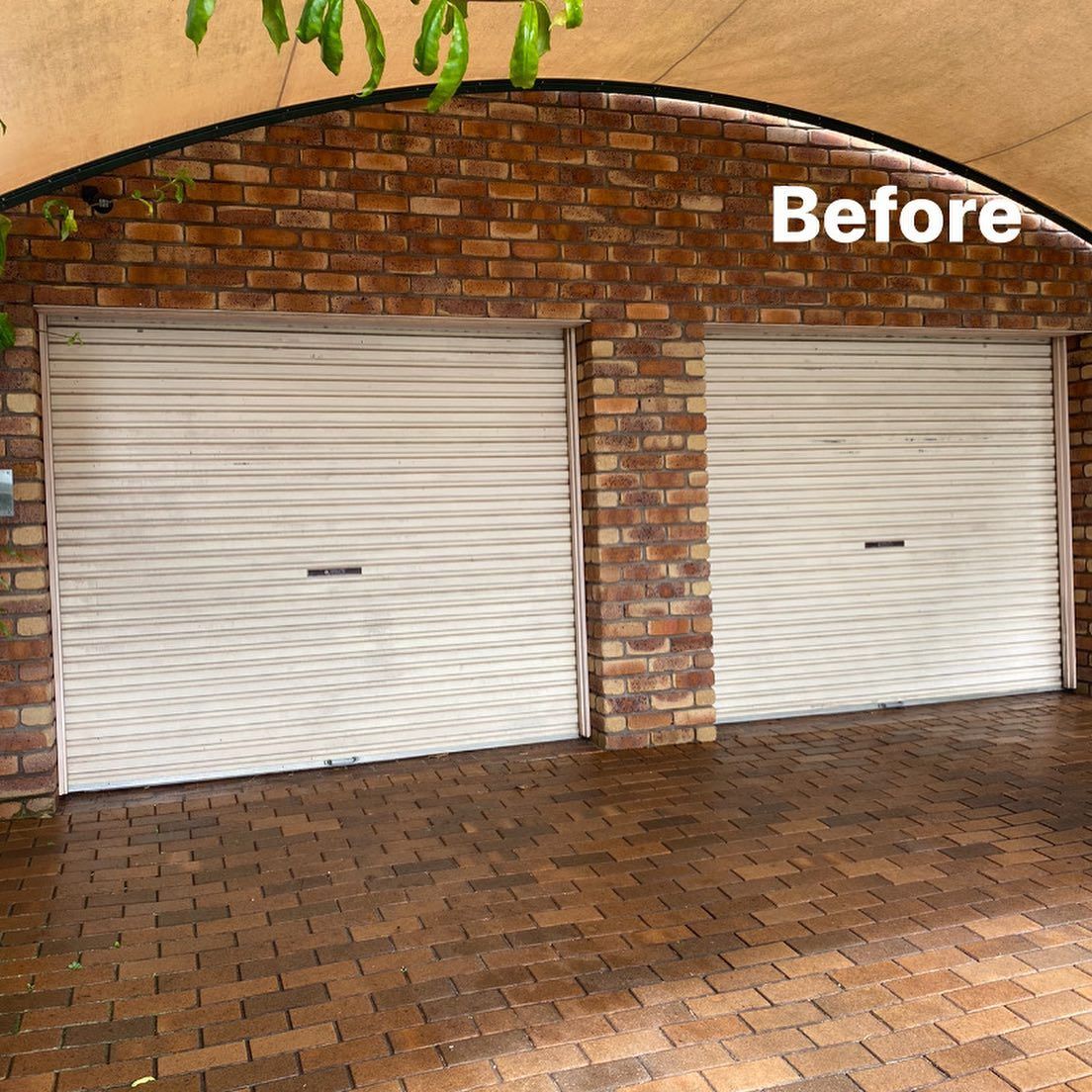 A before picture of a brick garage with white garage doors