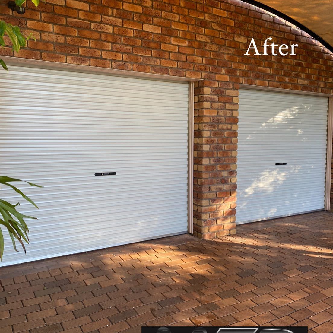 Two white garage doors are sitting next to each other on a brick wall.