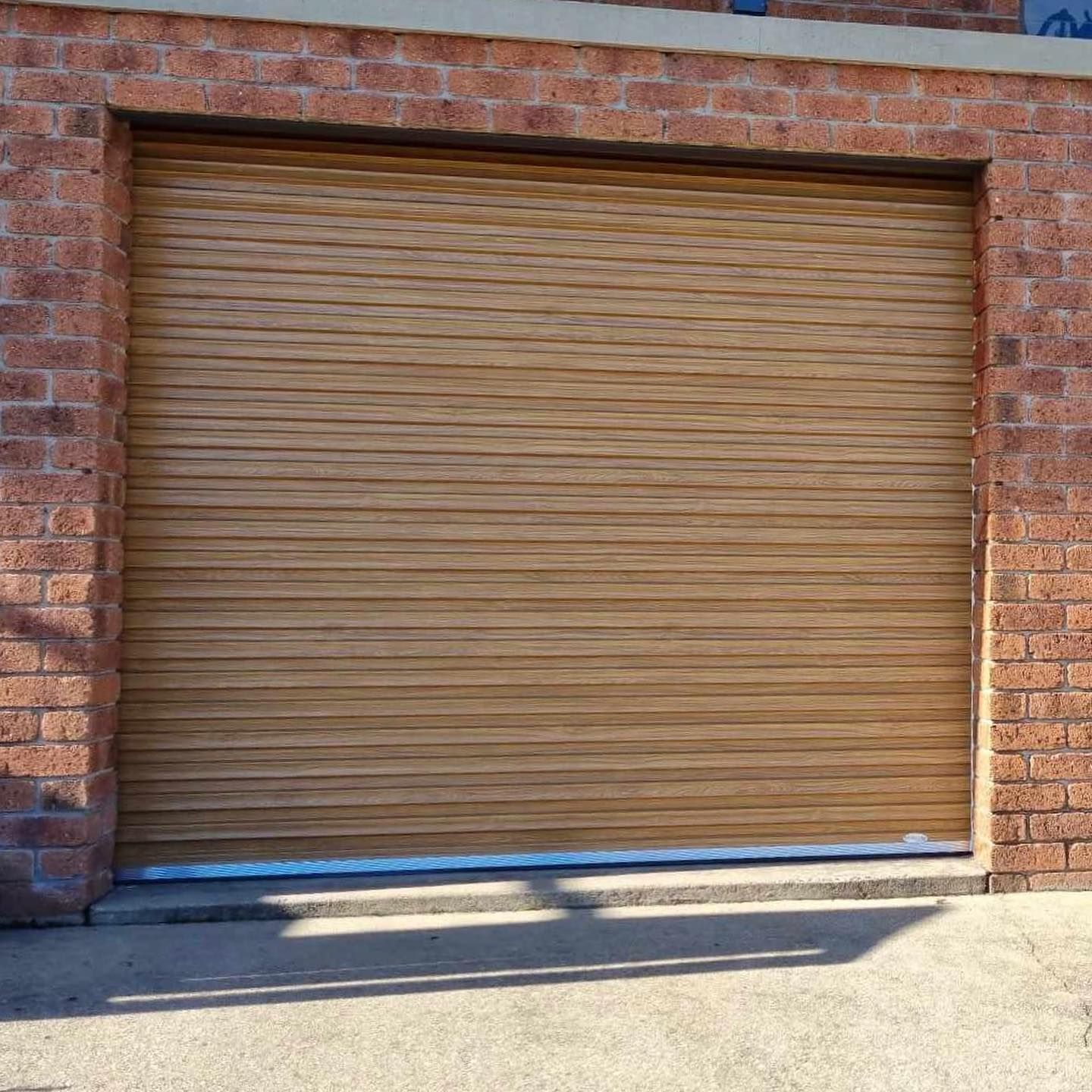 A wooden garage door is against a brick wall