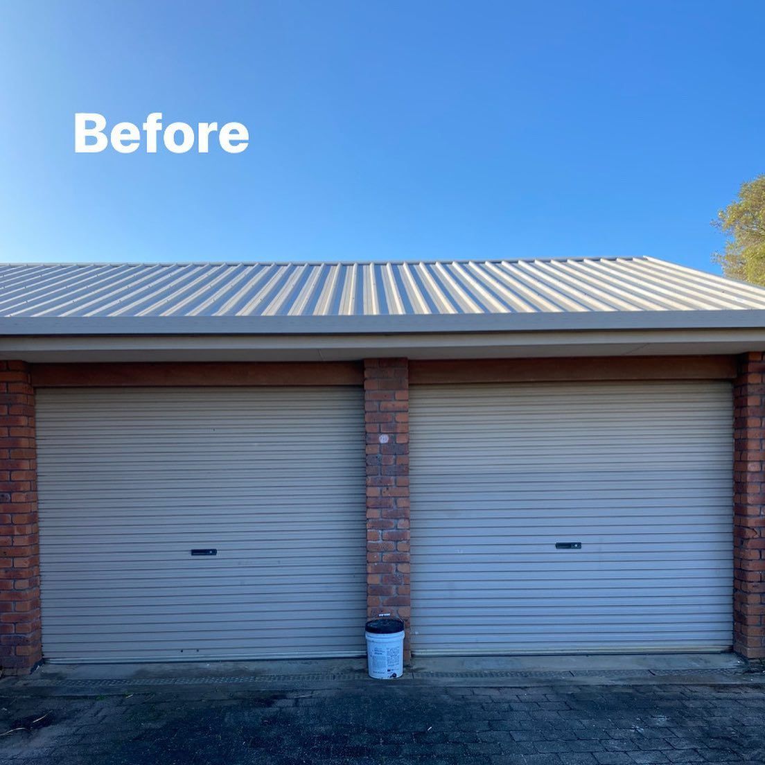 A garage with two white garage doors and a white roof.