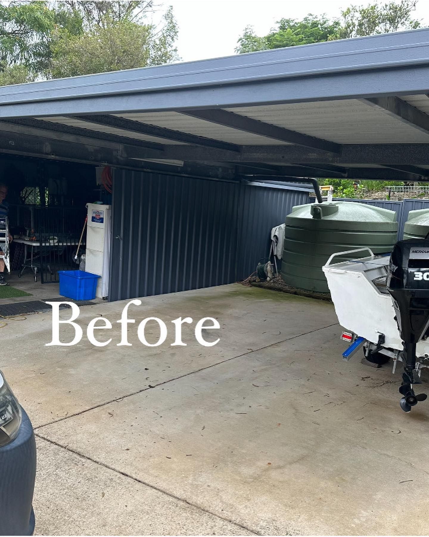 A boat is parked under a carport in front of a house.