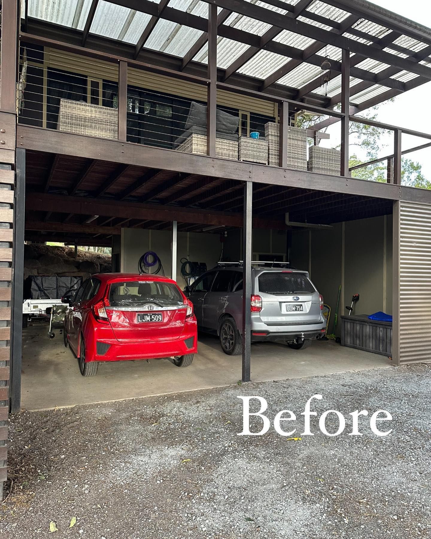 Two cars are parked under a deck in a garage.