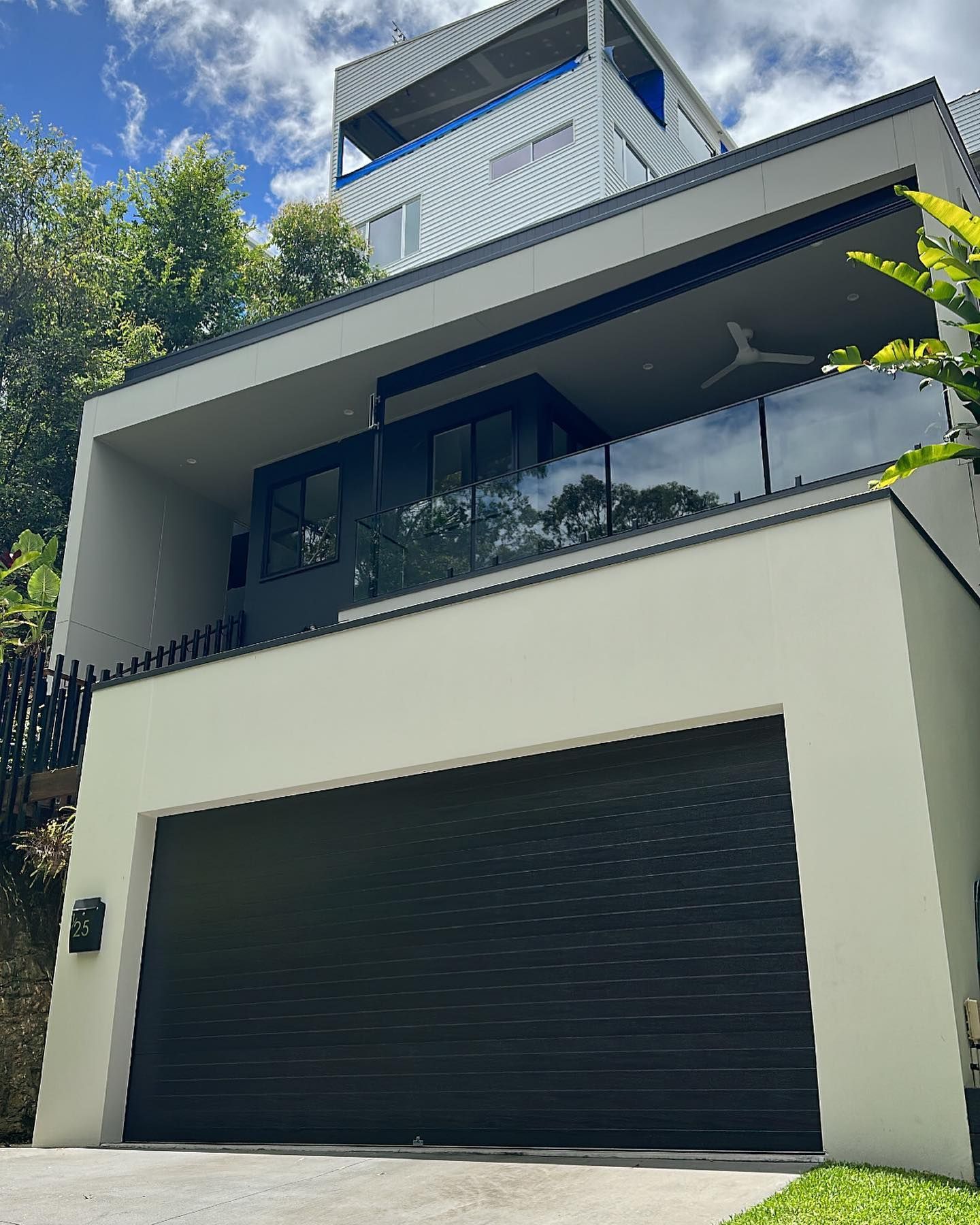 A large white house with a black garage door and a balcony.