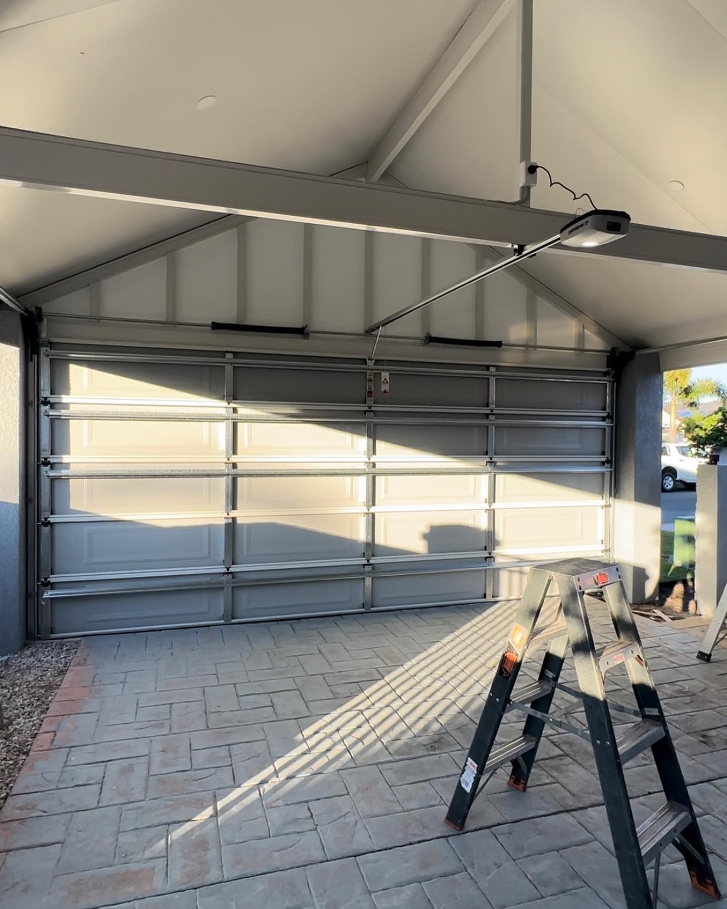 A ladder is sitting in a garage next to a garage door.