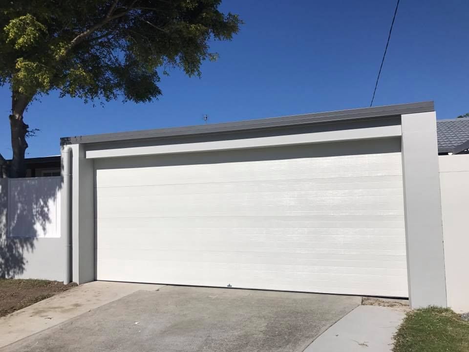 A white garage door with a tree in the background