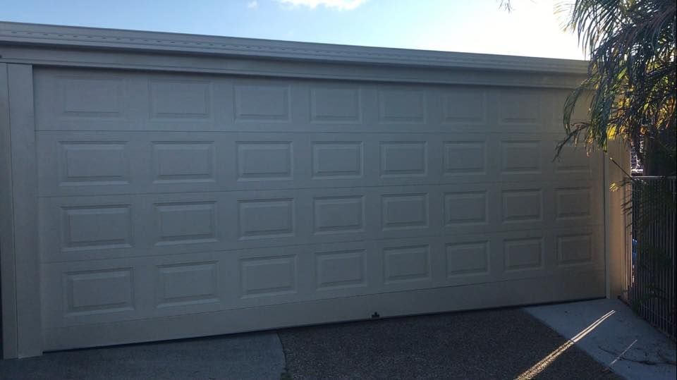 A large white garage door is open in a driveway.