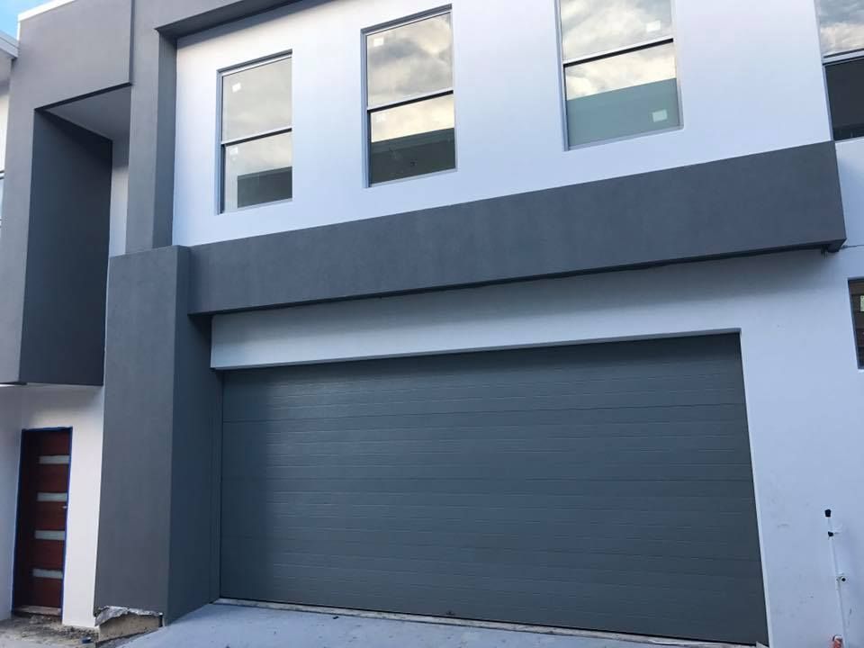 A large house with a gray garage door and a lot of windows.