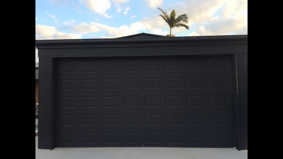 A black garage door with a palm tree on top of it.
