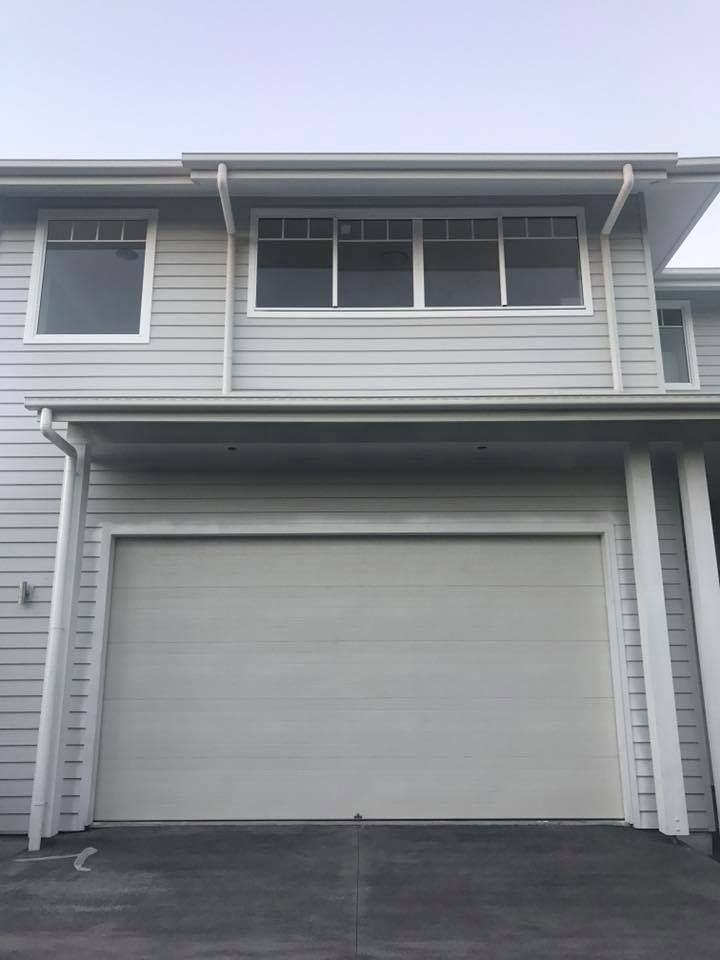 A white house with a garage door and a lot of windows.