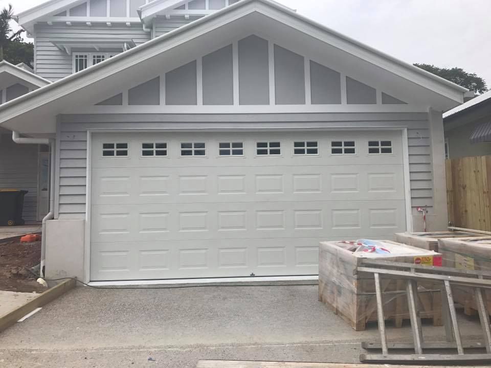 A white garage door with a ladder in front of it