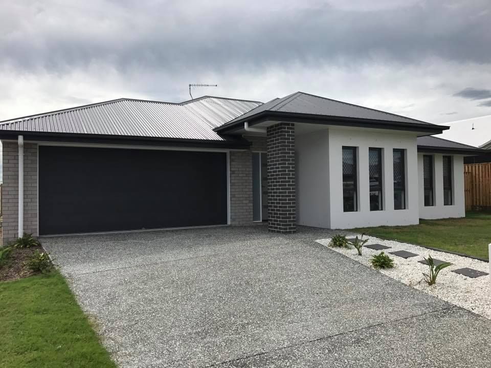 A white house with a black garage door and a driveway.