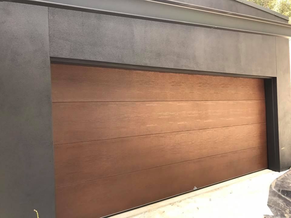 A brown garage door is sitting on the side of a building.