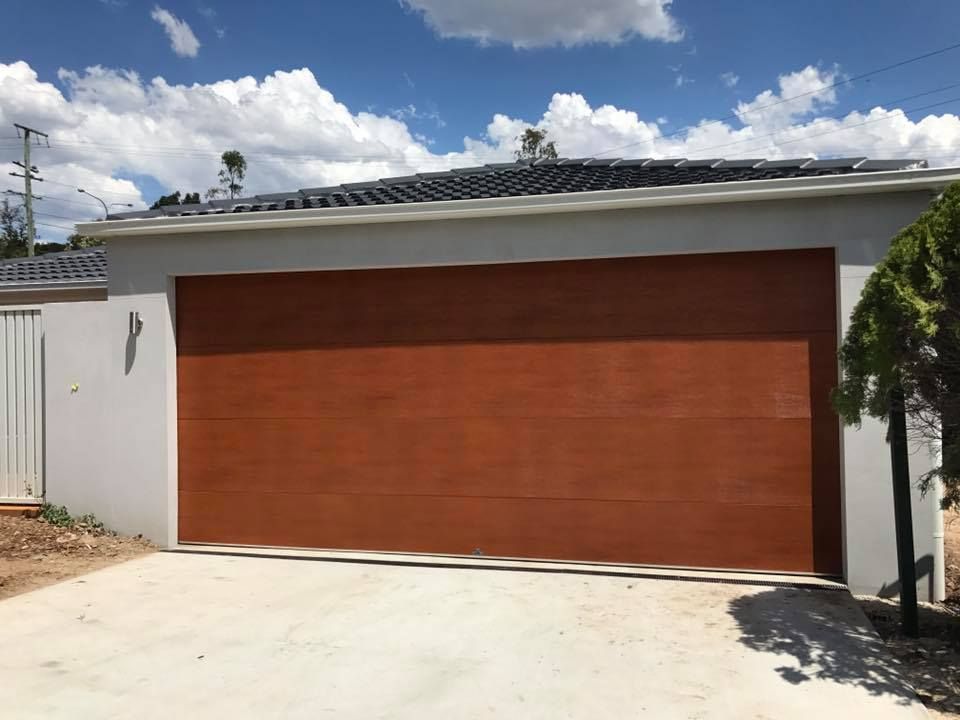 A large brown garage door is sitting in front of a house.