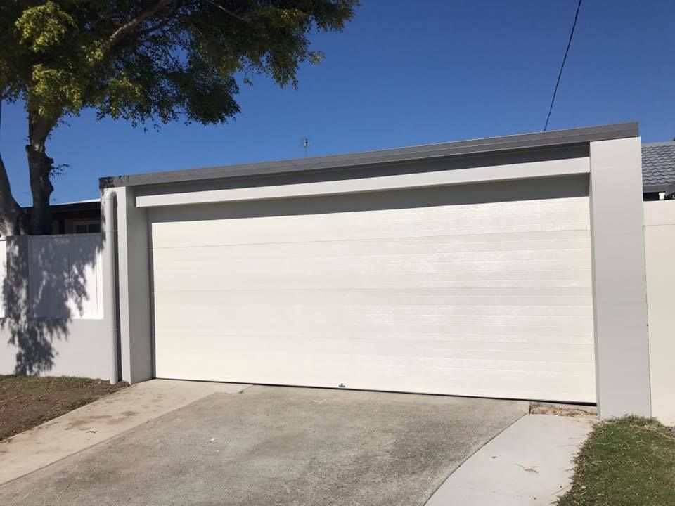 A white garage door is open in front of a house.