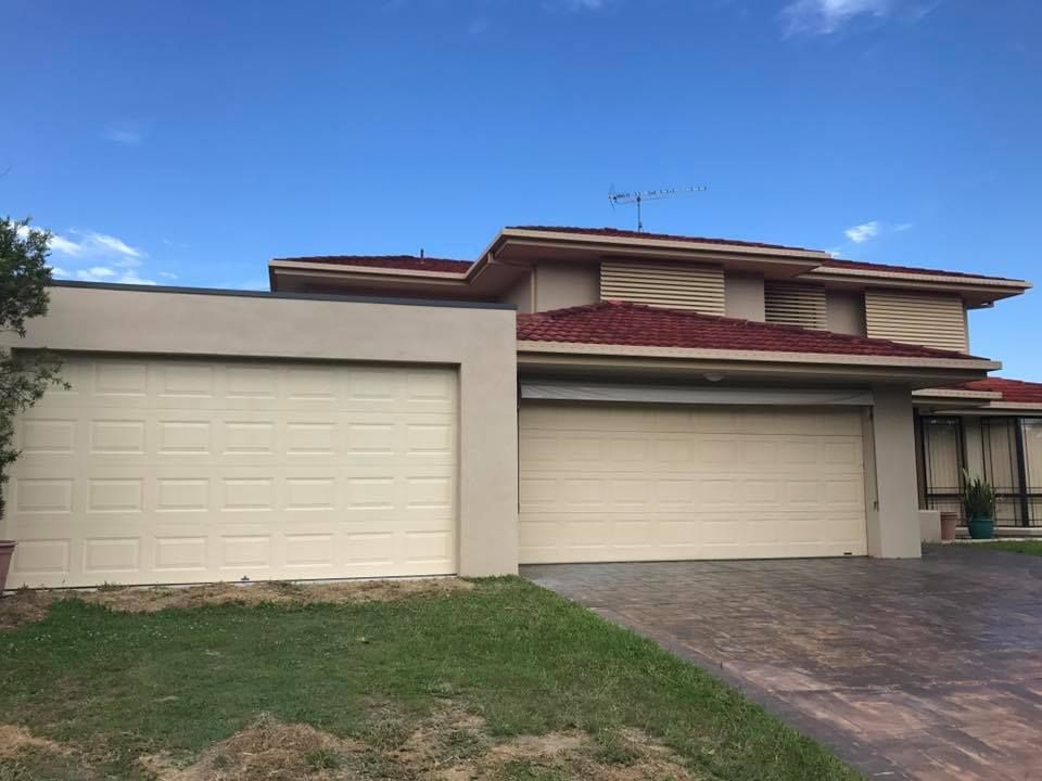 A large house with two garage doors and a red roof