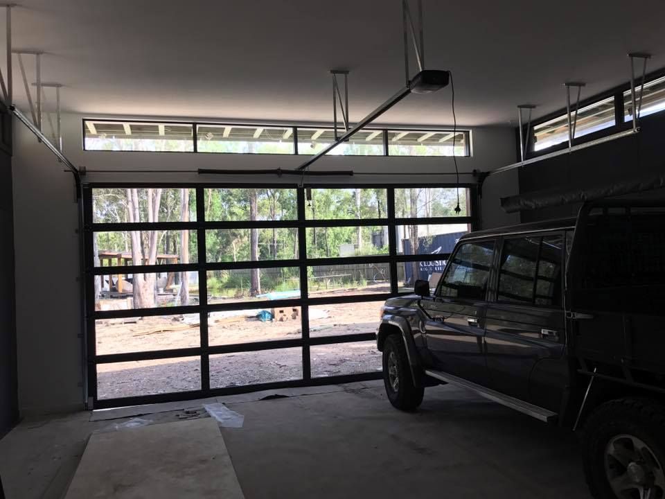 A truck is parked in a garage with a garage door open.