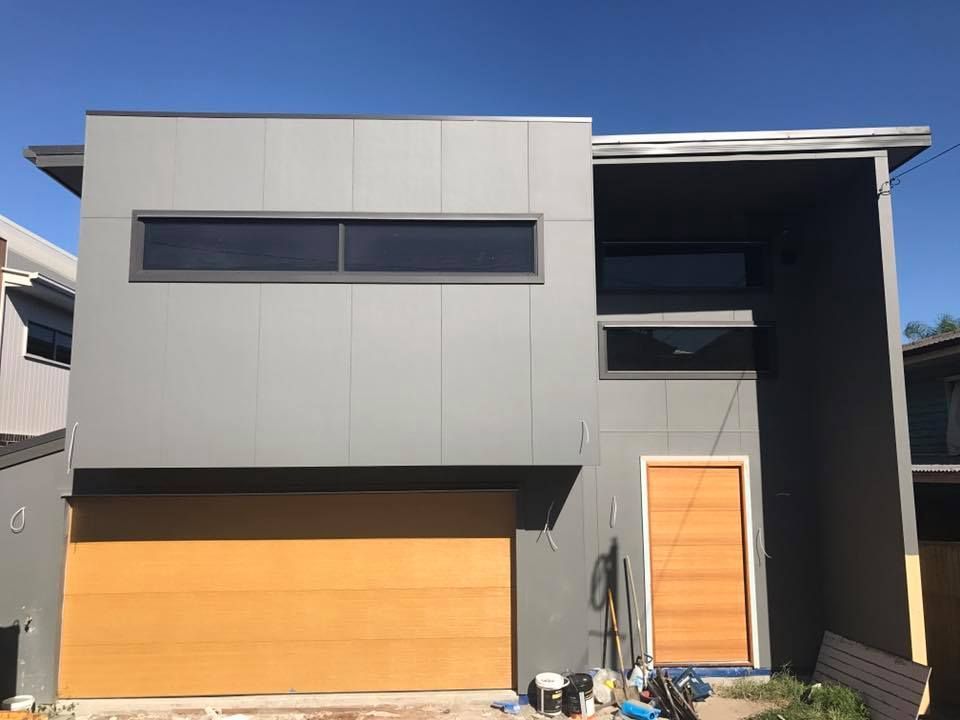 A modern house with a wooden garage door and a large window.