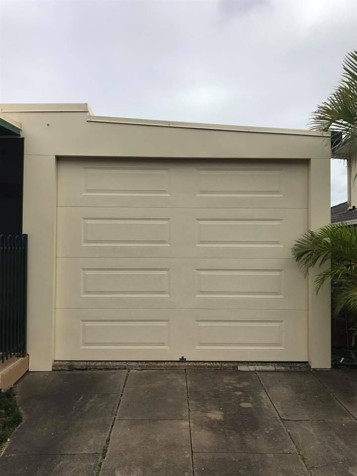 A white garage door is sitting in the driveway of a house.