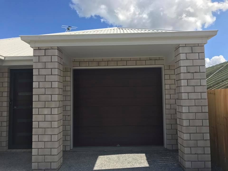 A white brick house with a brown garage door