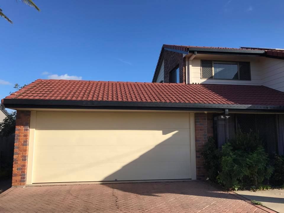 A house with a white garage door and a red roof