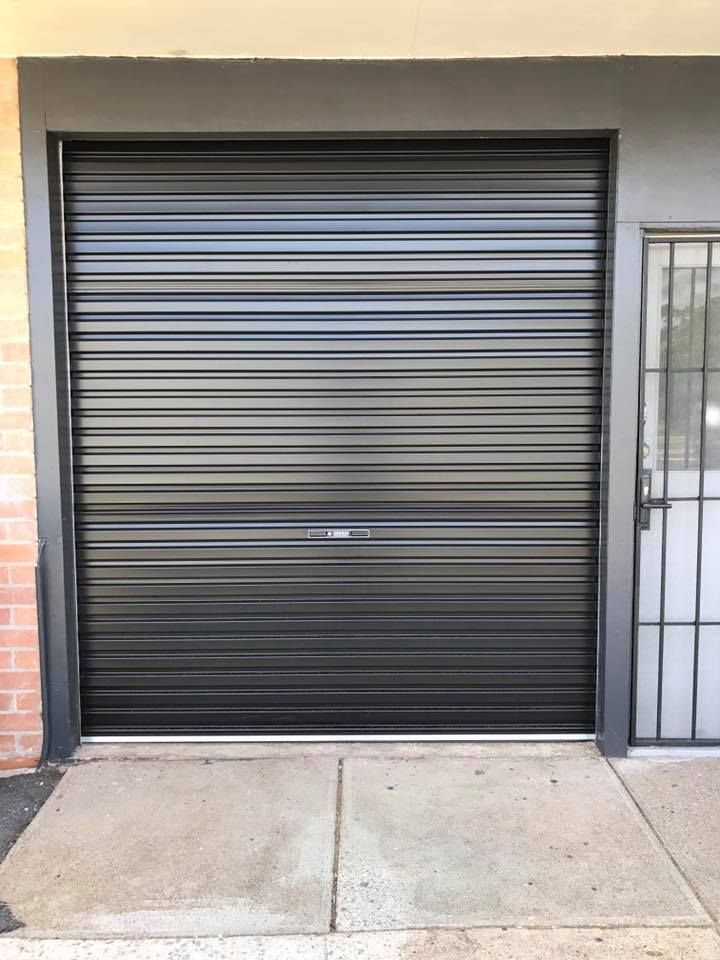 A black garage door is sitting in front of a brick building.