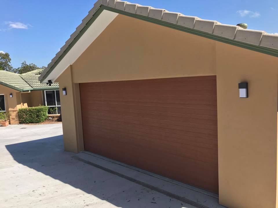 A house with a brown garage door and a green roof